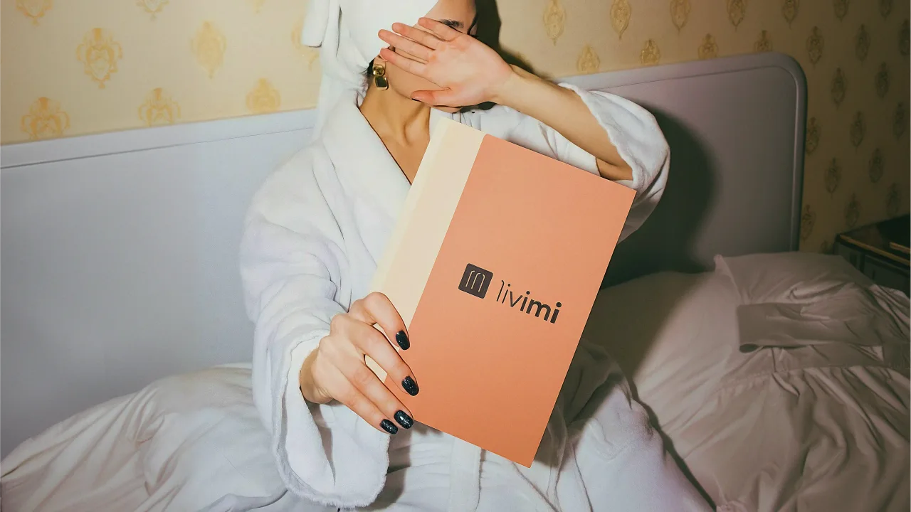 Woman in a bathrobe holding a Livimi brochure
